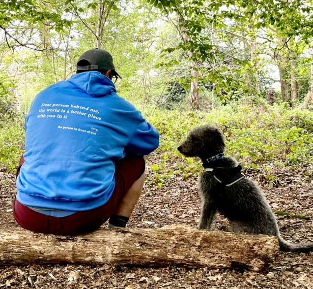 Person with dog wearing blue hoodie, back to camera